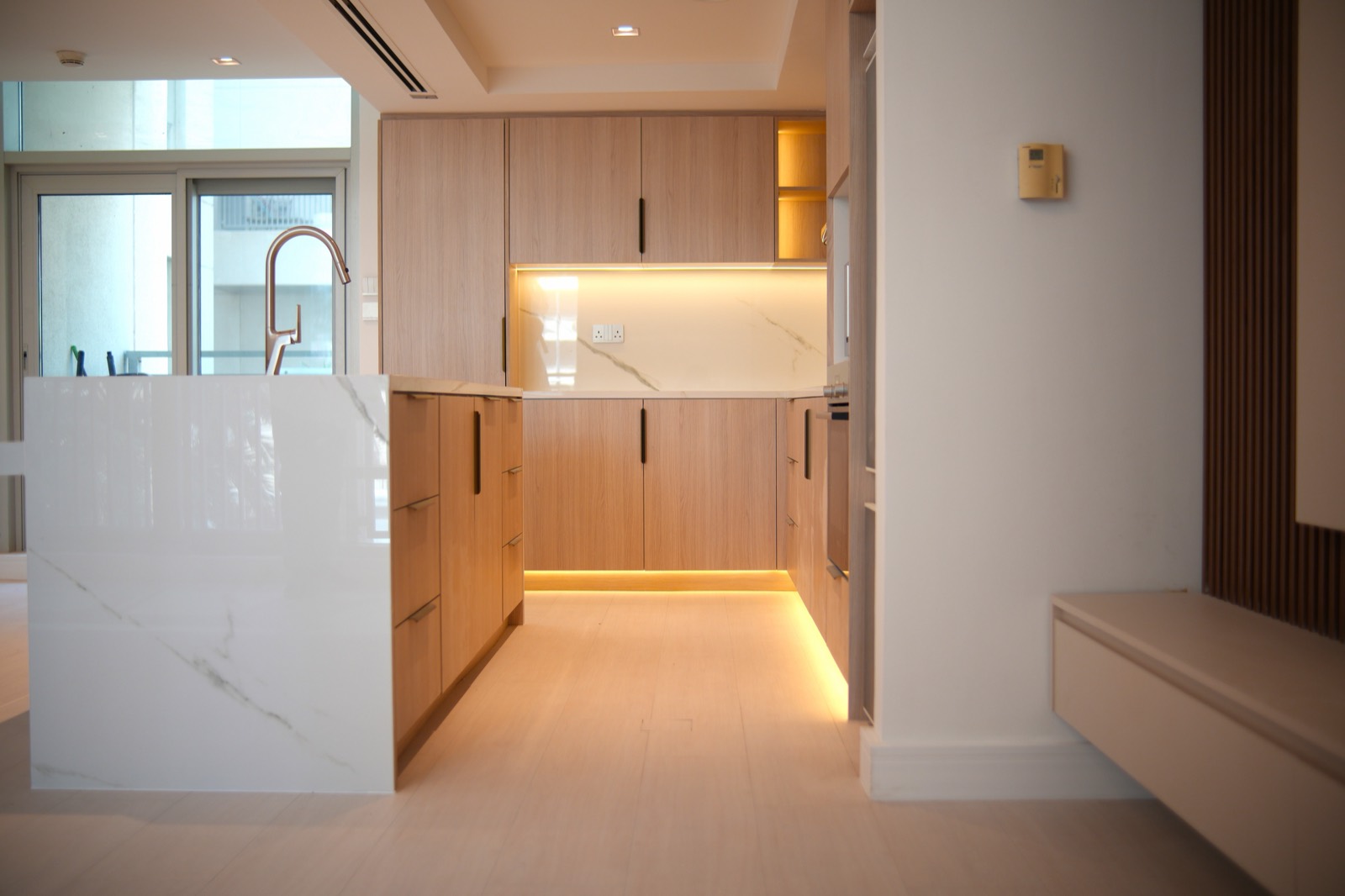 Bespoke kitchen with a waterfall stone island, integrated appliances and warm timber cabinetry
