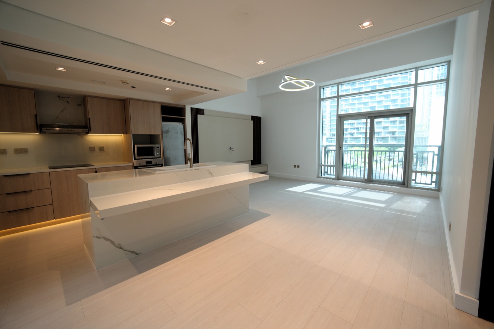 Open-plan living and kitchen with a waterfall stone island in a renovated apartment at The Lofts, Downtown Dubai