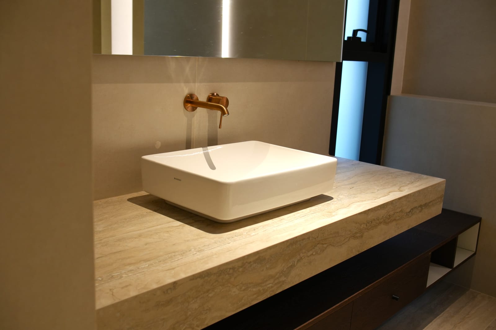 Ensuite bathroom with a travertine vanity, vessel basin and brushed-copper wall tap