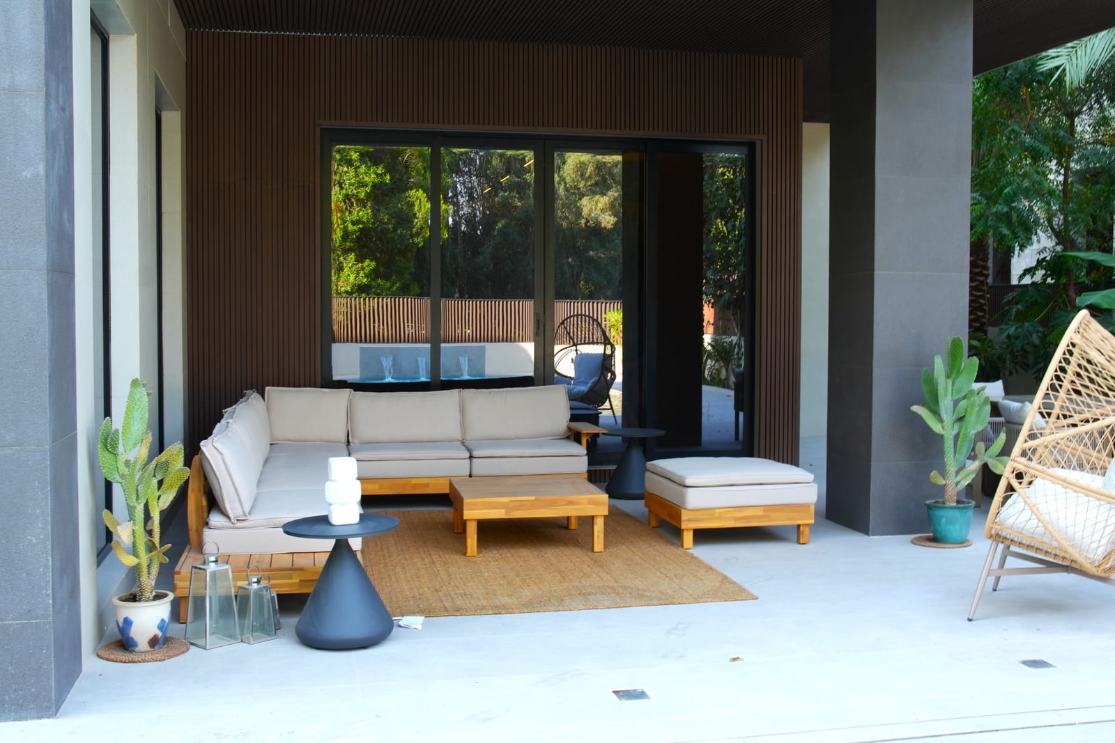 Covered outdoor lounge with a timber-slatted ceiling and modular seating beside the pool